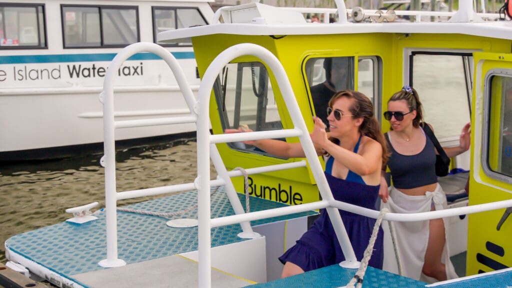 a woman stepping off a fire island water taxi using a ladder