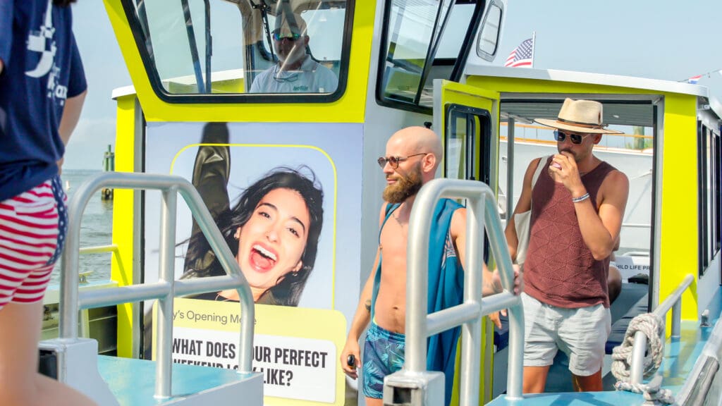 an advertisement displayed on a Fire Island Water Taxi with a group of friends leaving the vessel