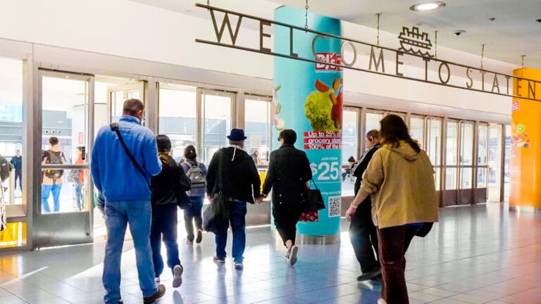 St George Terminal advertisements with people walking in front of the welcome sign