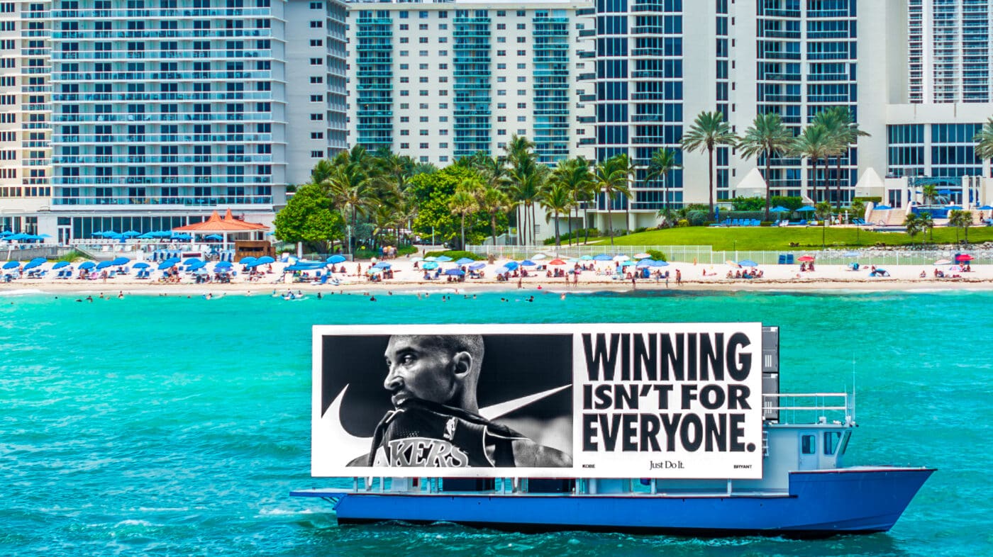 Ferry advertising for Nike showcases a large billboard with a basketball player on turquoise waters near beachfront skyscrapers; outdoor advertising.